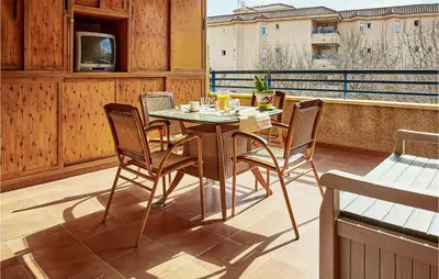 a table and chairs on a balcony with a television at Pet Friendly Apartment in Sanlúcar de Barrameda