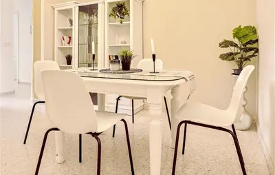 a white dining room table with white chairs and a candle at Pet Friendly Apartment in Sanlúcar de Barrameda