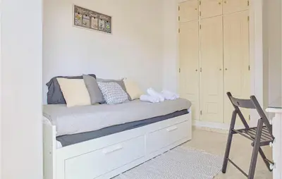 a bedroom with a bed with a chair and a desk at Pet Friendly Apartment in Sanlúcar de Barrameda