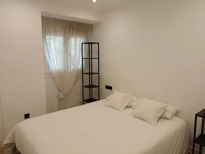 a white bed with white pillows and a window at Apartamento Arsenio Beach in Cádiz