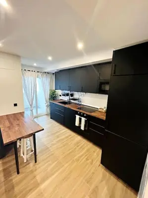 a kitchen with a black refrigerator and a wooden floor at Apartamento Arsenio Beach in Cádiz