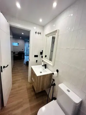 a white bathroom with a toilet and a sink at Apartamento Arsenio Beach in Cádiz
