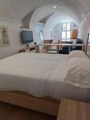 a bedroom with a large white bed with a desk at La Bodeguita in Jerez de la Frontera