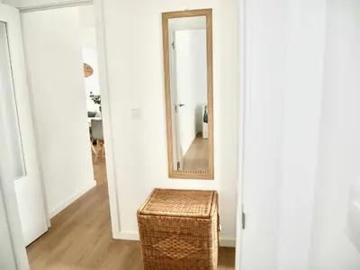 a wicker stool in a hallway with a mirror at Casa Carivid - en el centro y con parking gratis - in Sanlúcar de Barrameda