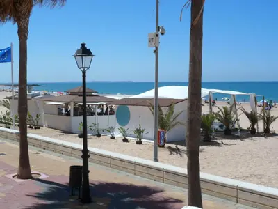 a street light next to a beach with palm trees at Hotel Macavi Playa in Rota