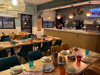 a restaurant with wooden tables and chairs and a counter at Hotel Macavi Playa in Rota