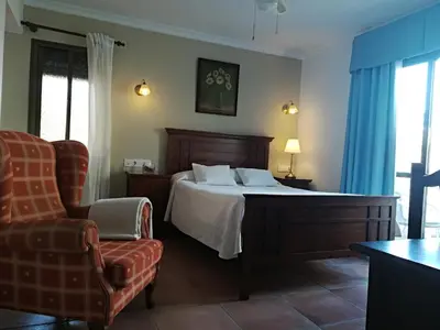 a bedroom with a large bed and a chair at Hotel Macavi Playa in Rota