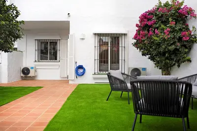 a patio with chairs and a plant with pink flowers at MARIA DEL MAR SEA APARTMENT in Chiclana de la Frontera