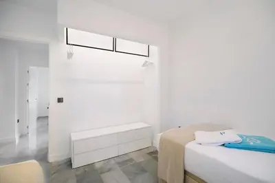 a white bedroom with a bed and a window at MARIA DEL MAR SEA APARTMENT in Chiclana de la Frontera