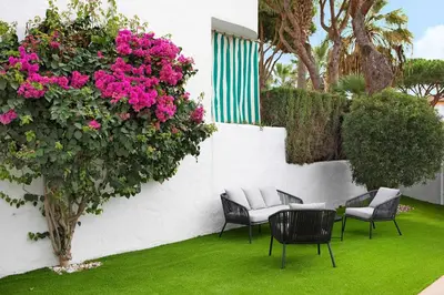 a patio with chairs and a table and pink flowers at MARIA DEL MAR SEA APARTMENT in Chiclana de la Frontera