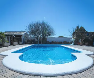 a swimming pool with blue water in a yard at Villa Encanto in Conil de la Frontera