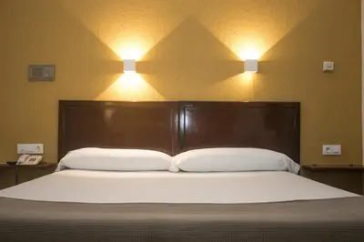 a bed with two pillows and two lights on the wall at Hotel Caribe in Rota