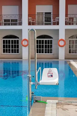 a swimming pool with a white chair in the water at Hotel Caribe in Rota