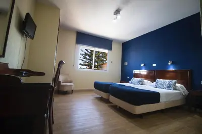 a bedroom with a large bed with a blue wall at Hotel Caribe in Rota
