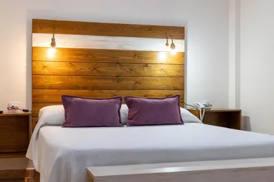 a bedroom with a bed with two purple pillows at Puerta de Algadir in El Puerto de Santa María