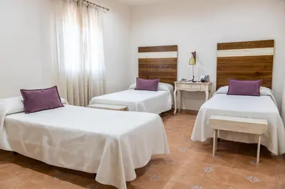 a room with three beds with purple pillows at Puerta de Algadir in El Puerto de Santa María