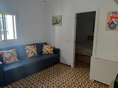 a living room with a blue couch and a bedroom at Estudio Alicia in Rota