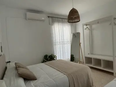 a white bedroom with a bed and a window at VILLA SALMONETE in Sanlúcar de Barrameda