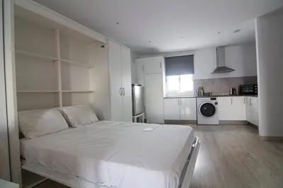 a white bedroom with a bed and a kitchen at Apartamento Herrería centro in El Puerto de Santa María