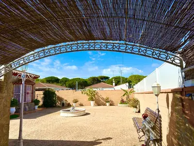 an arch over a patio with a bench and a fountain at Chalet Aguacate in Chiclana de la Frontera