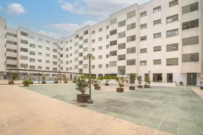 a large white building with potted plants in a courtyard at Apartamento céntrico con piscina, temporada in El Puerto de Santa María
