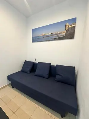a blue couch in a room with a picture on the wall at Apartamento céntrico con piscina, temporada in El Puerto de Santa María