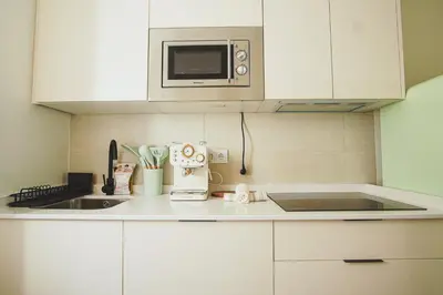 a kitchen with white cabinets and a microwave at Ocean View Ha Apartment in Cádiz