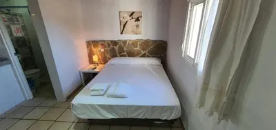 a small bed in a small room with a window at Estudios con piscina compartida en Complejo Rural el Mayorazgo in Cádiz