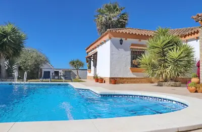 a swimming pool in front of a house with palm trees at Casa de los Abuelos in Hozanejos