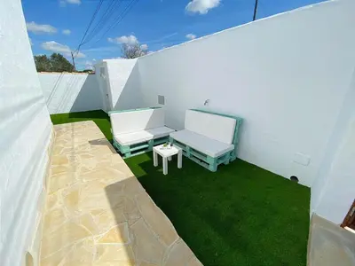 a patio with two chairs and a table and grass at GALDANA in Chiclana de la Frontera