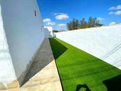 a white wall with green grass on the side of it at GALDANA in Chiclana de la Frontera