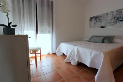 a white bedroom with a bed and a chair at ConiL Casa H&L in Conil de la Frontera