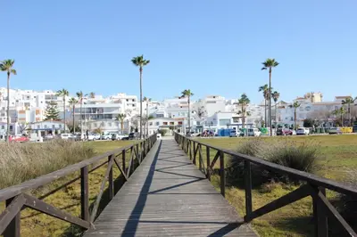 a wooden boardwalk over a beach with buildings in the background at ConiL Casa H&L in Conil de la Frontera