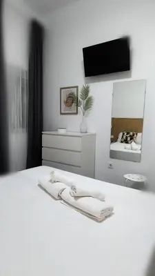 a bedroom with a white bed and a mirror at Apartamento Poniente Sanlúcar - Centro in Sanlúcar de Barrameda