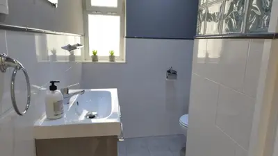 a white bathroom with a sink and a toilet at Apartamento Poniente Sanlúcar - Centro in Sanlúcar de Barrameda