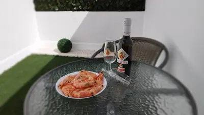 a glass table with a bowl of shrimp and a bottle of wine at Apartamento Poniente Sanlúcar - Centro in Sanlúcar de Barrameda