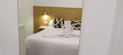 a bedroom with a bed with white sheets and pillows at Apartamento Poniente Sanlúcar - Centro in Sanlúcar de Barrameda
