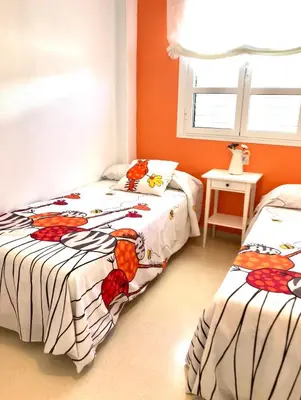 two beds in a room with orange walls at Apartamento DUPLEX CRUZ DEL MAR in Chipiona