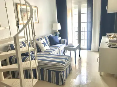 a living room with a staircase and a couch at Apartamento DUPLEX CRUZ DEL MAR in Chipiona