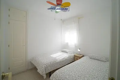 a bedroom with two beds and a ceiling fan at Apartamento Cigüeña in Sanlúcar de Barrameda