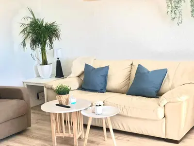 a living room with a couch and two tables with blue pillows at Frente al mar, preciosas vistas, piscinas , valdelagrana in El Puerto de Santa María