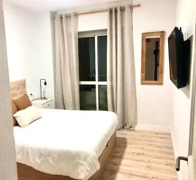 a white bedroom with a bed and a window at Frente al mar, preciosas vistas, piscinas , valdelagrana in El Puerto de Santa María