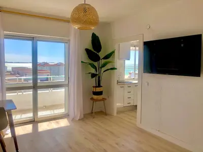 a living room with a plant and a large window at Frente al mar, preciosas vistas, piscinas , valdelagrana in El Puerto de Santa María