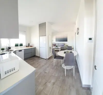 a kitchen and living room with a table and chairs at Playa Doñana 2 in Sanlúcar de Barrameda
