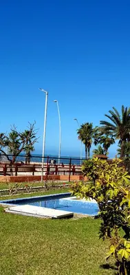 a swimming pool next to the ocean with palm trees at Playa Doñana 2 in Sanlúcar de Barrameda