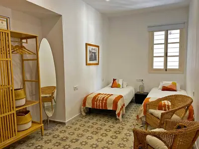 a room with two beds and a chair in it at Apartamento Intramuros - Ole Solutions in Jerez de la Frontera
