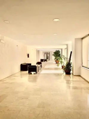 a long hallway with couches and plants in a building at Apartamento nuevo con piscina, temporada in El Puerto de Santa María