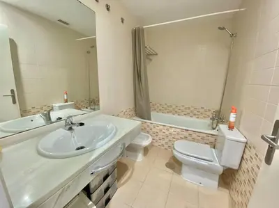 a bathroom with a sink and a toilet and a mirror at Apartamento nuevo con piscina, temporada in El Puerto de Santa María