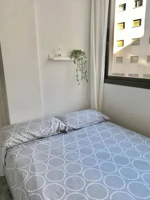 a bed in a white room with a window at Apartamento nuevo con piscina, temporada in El Puerto de Santa María
