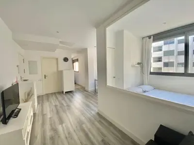 a living room with a large window and a couch at Apartamento nuevo con piscina, temporada in El Puerto de Santa María